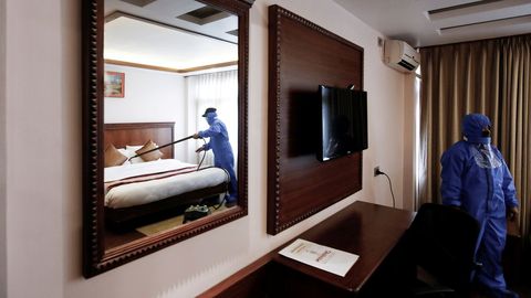 Dos empleados con trajes de proteccin desinfectan la habitacin de un hotel en Nepal
