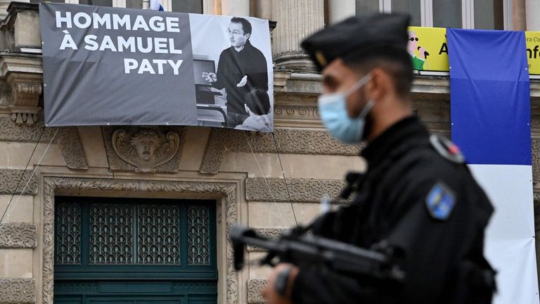 Un policia pasa al lado de un cartel en homenaje al profesor decapitado por un islamista