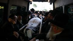 Amigos y familiares del rabino Elimelech Wasserman rezan en su coche fúnebre.