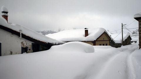 Un vehculo cubierto de nieve, en el pueblo asturiano de Pajares