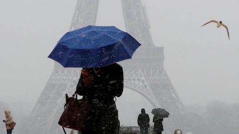 Una mujer sostiene un paraguas para protegerse de la nieve que cae cerca de la Torre Eiffel, en París