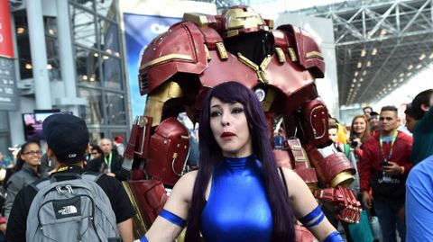 Una mujer vestida de la miembro de los X-Men Psylocke (Mariposa Mental, en Espaa) ante una gran armadura de Iron Man.