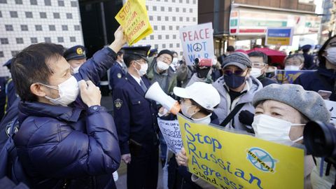 Personas gritan consignas mientras protestan contra la invasión rusa de Ucrania, frente a la embajada rusa en Tokio, Japón.