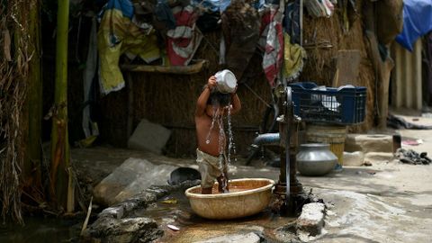 Un nio indio se echa agua por encima para luchar contra las altas temperaturas que se registran. 