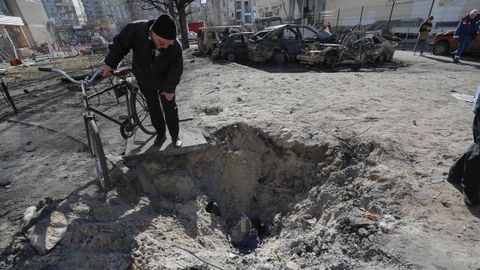 Un hombre observa el crter de un proyectil un da despus de un bombardeo en una zona residencial de Kiev, Ucrania.