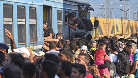 Cientos de personas se agolpan alrededor de un tren en Gevgelija, Macedonia, junto a la frontera con Serbia