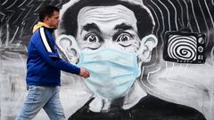 Un hombre pasando ante un grafiti del personaje don Ramn con mascarilla, en Montevideo