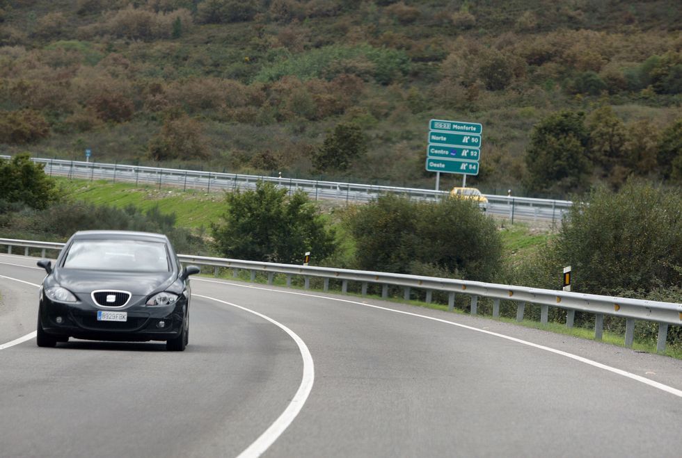 Un coche circula por la LU-546 entre Ribas Altas y A �spera, con el trazado de la v�a r�pida al fondo. 