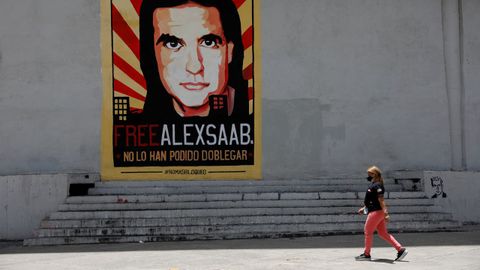Una mujer paseando en Caracas ante un cartel que pide la libertad de Álex Saab.