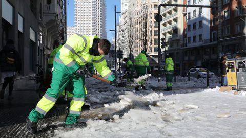 Operarios de limpieza trabajan limpiando la nieve en una calle de Madrid