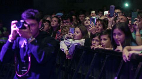 Un periodista fotografía la actuación de Ana Mena con los jóvenes de la primera fila detrás de él jaleando a la cantante