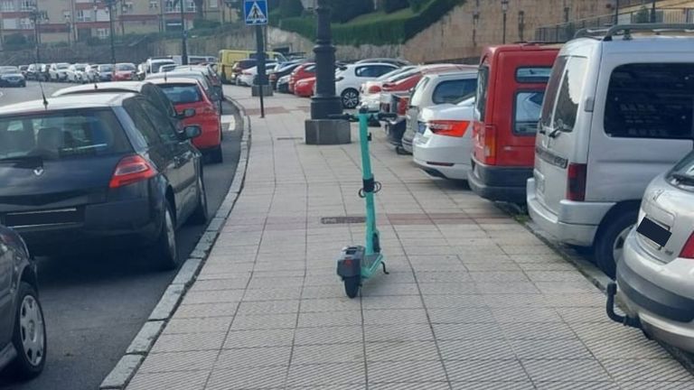 Patinete eléctrico «abandonado» en mitad de una acera en Oviedo.
