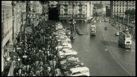 La acera de los cantones abarrotada de coruñeses en una día de paseo, mientras los trolebuses pasan ante el Obelisco, en una imagen tomada a finales de los años 50