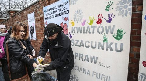 Una mujer se pinta la palma de la mano para dejar su huella en el muro de la furia  ante la sede del Partido de Ley y Justicia en Varsovia, Polonia. 