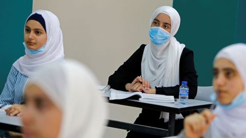 Estudiantes palestinos escuchan a su profesor mientras un nuevo año escolar empieza parcialmente entre la preocupación por la propagación del coronavirus